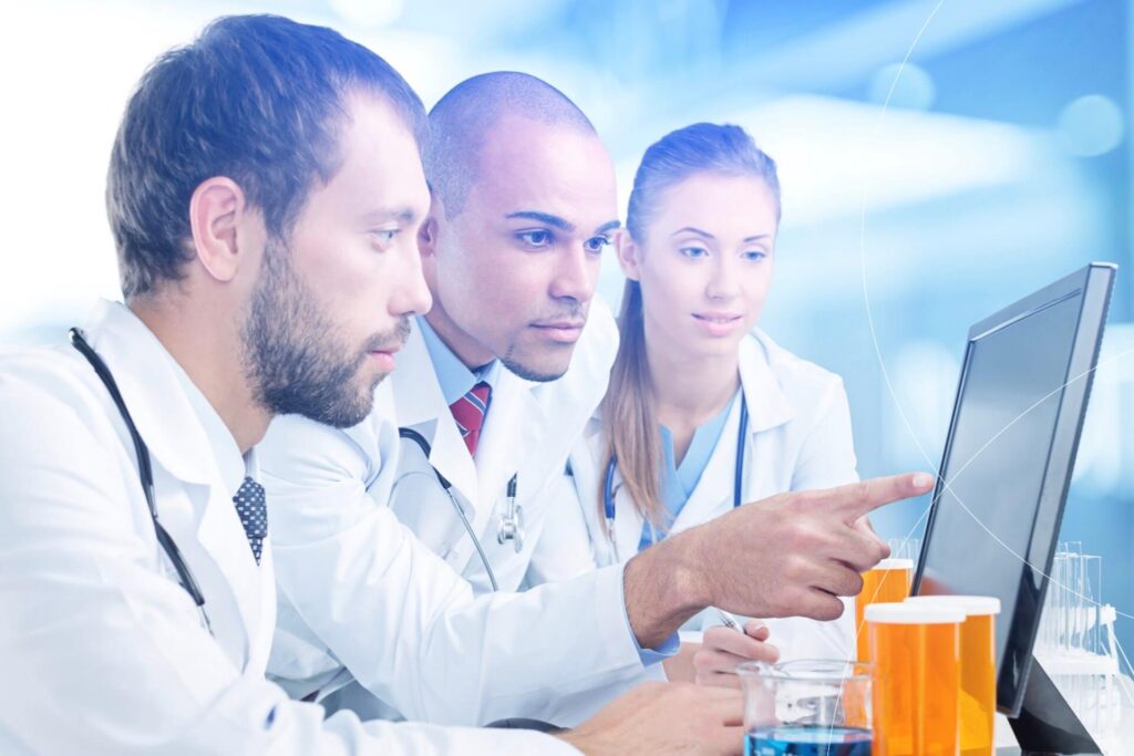 Three professionals collaborating in front of a computer monitor, reviewing cardiovascular study data